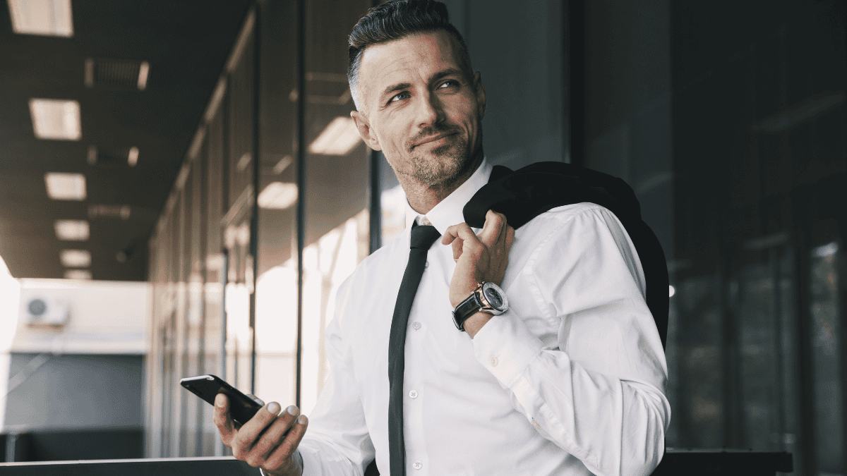 Confident business leader standing with a phone on his hand, reflecting on leadership confidence and decision-making in the workplace.